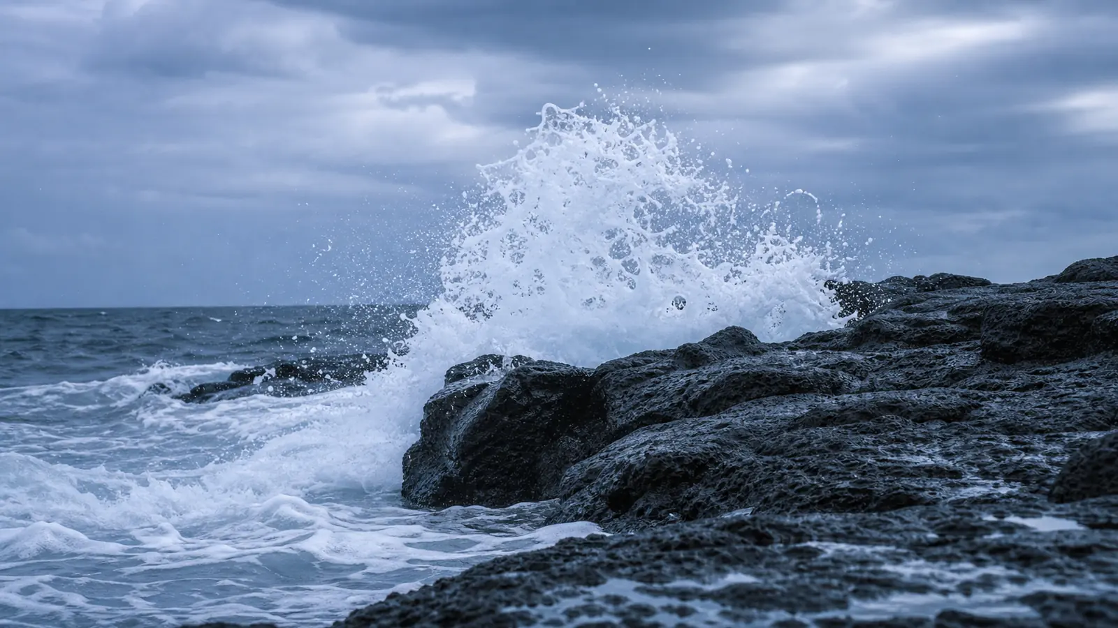 White waves breaking against black volcanic rock on the coast of Jeju