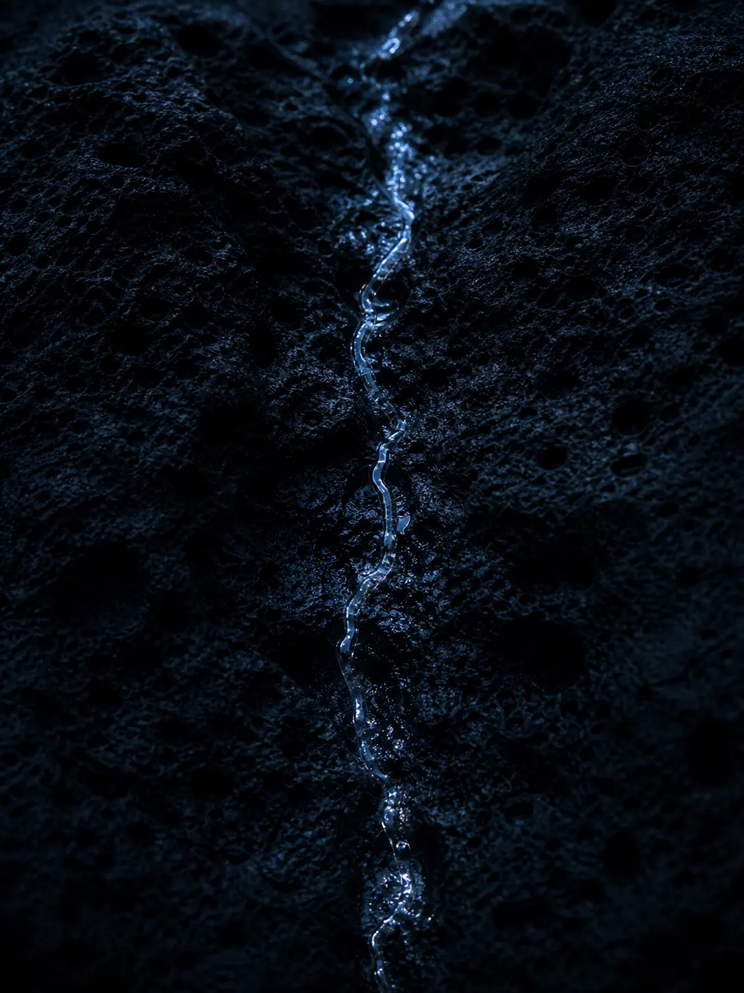 A narrow stream of water running between dark volcanic rock columns